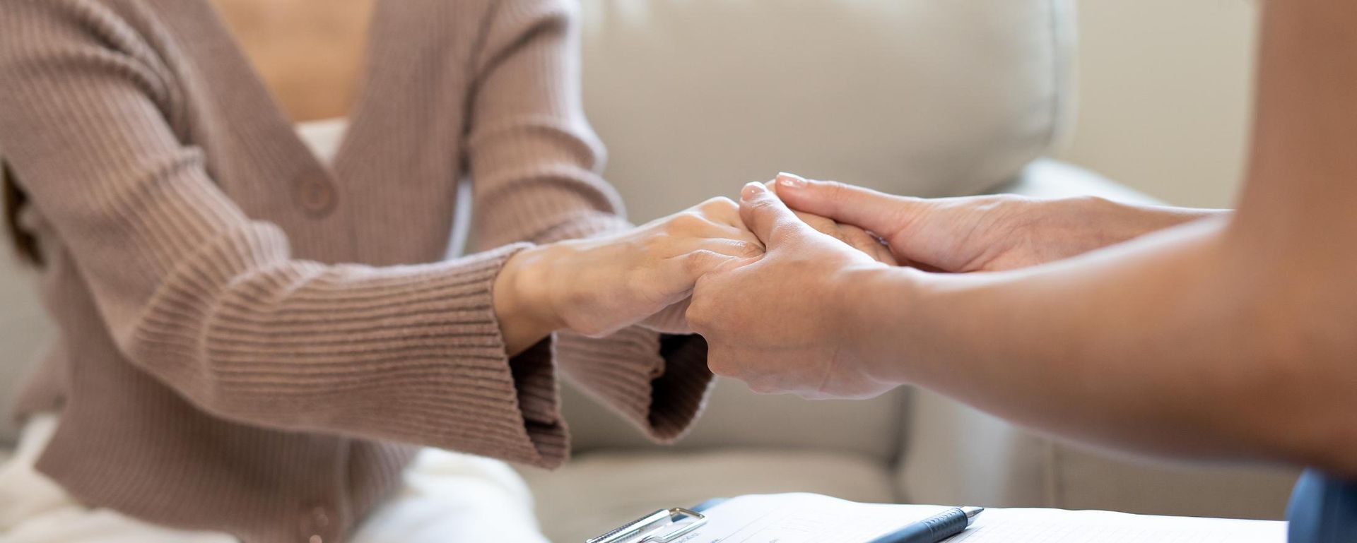 Dos personas tomadas de la mano, ofreciéndose apoyo en un entorno de asesoramiento.
