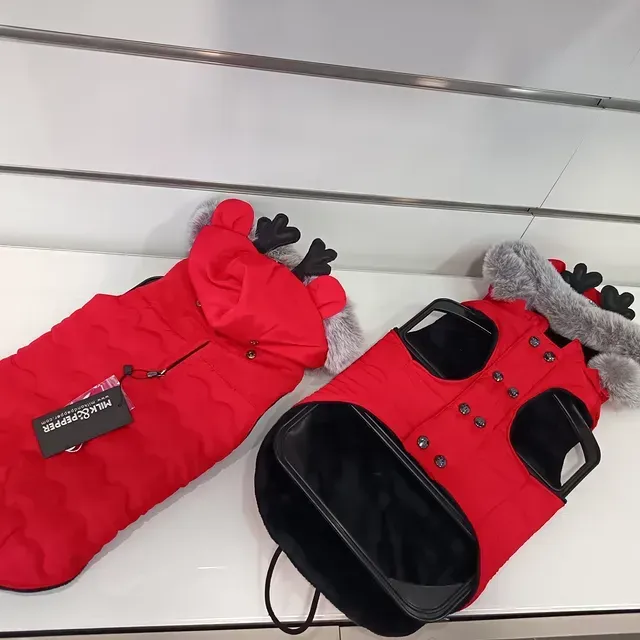 Deux manteaux d'hiver rouges pour animaux de compagnie, avec bordures noires et capuches en fourrure, exposés en magasin.