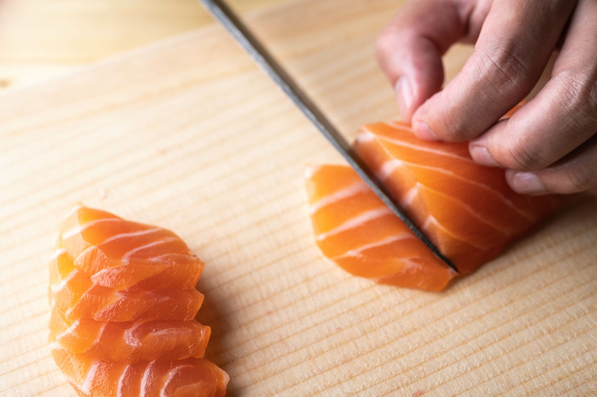 Découpe sur une planche de sashimis de saumon