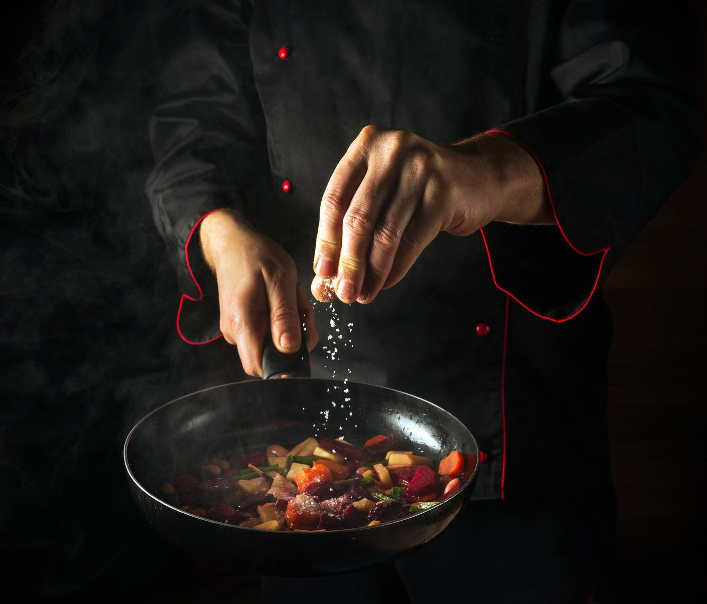 Chef cuisinier versant du sel dans son wok