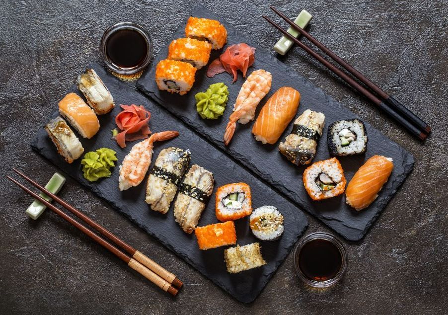 Ardoises avec des sushis, des california rolls et des baguettes