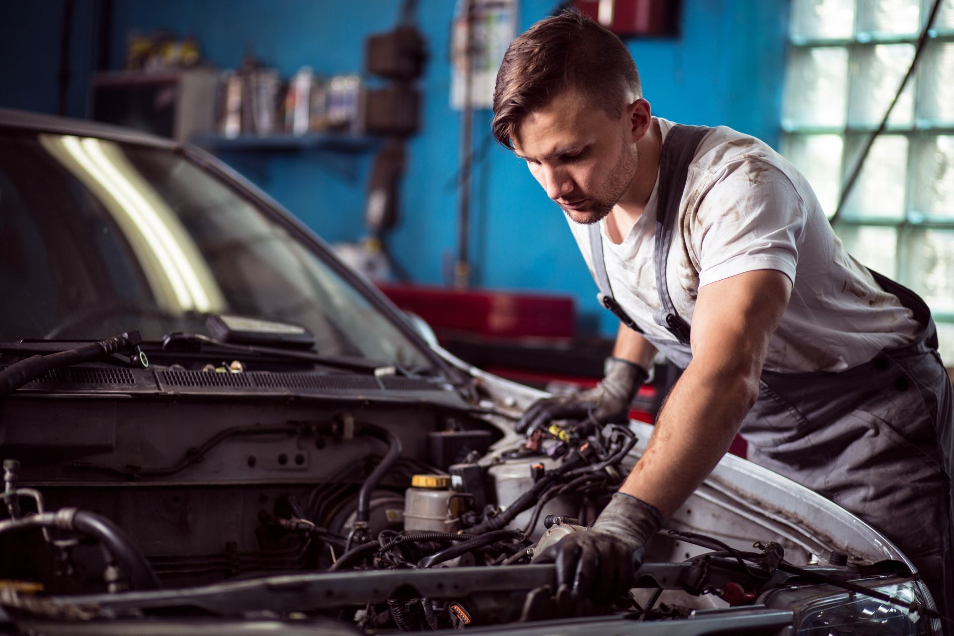 Un hombre está trabajando en el motor de un coche en un garaje