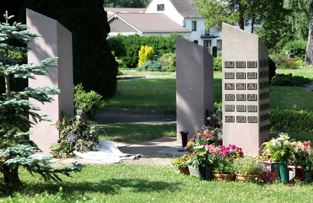 Ein Friedhof mit Blumen und einem Haus im Hintergrund