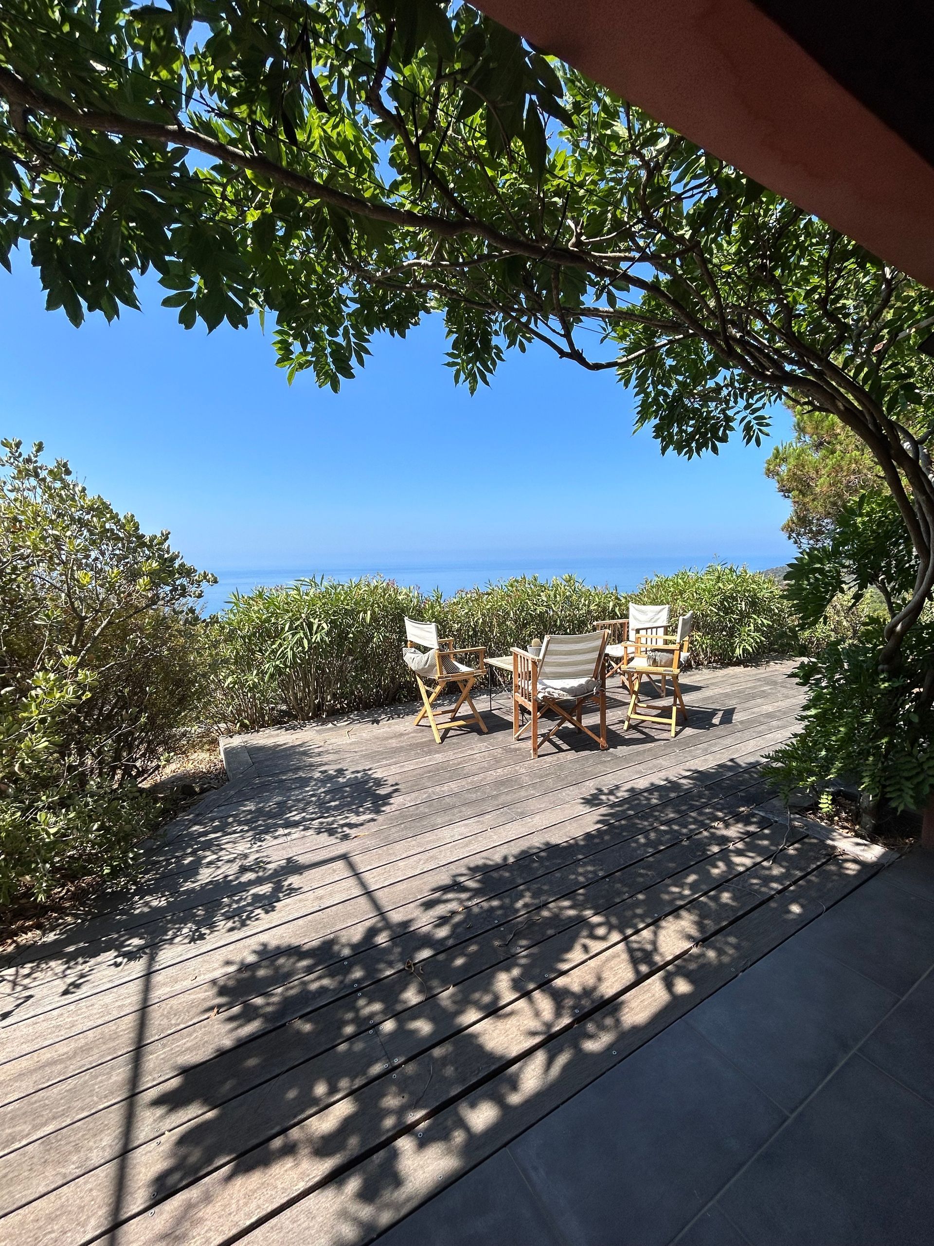 Une terrasse en bois avec une table et des chaises blanches