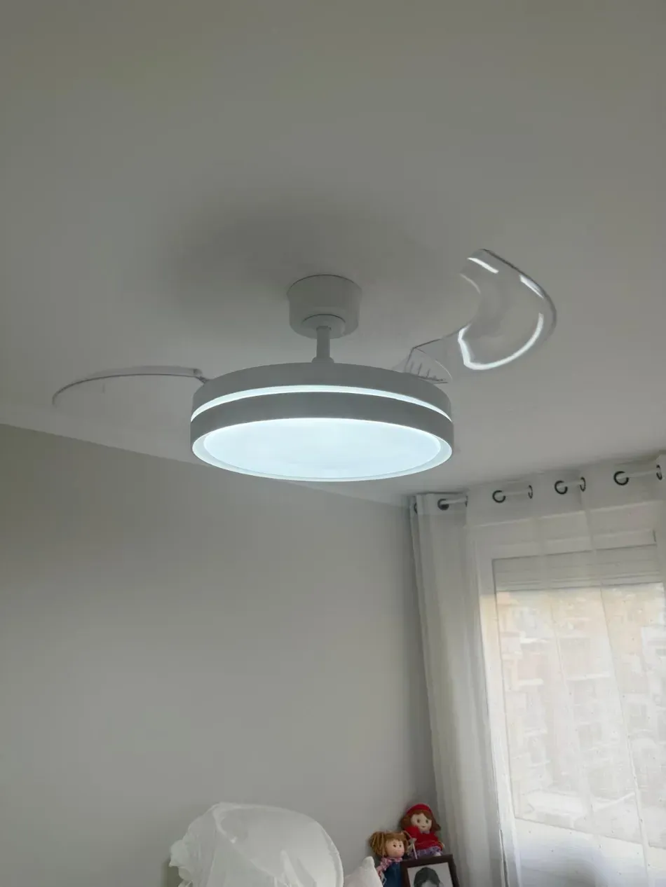 Lámpara de techo moderna con brazos curvos en una habitación blanca junto a una ventana.