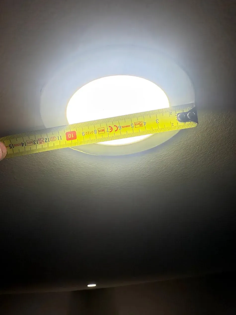 Cinta métrica extendida sobre una lámpara de techo brillante.