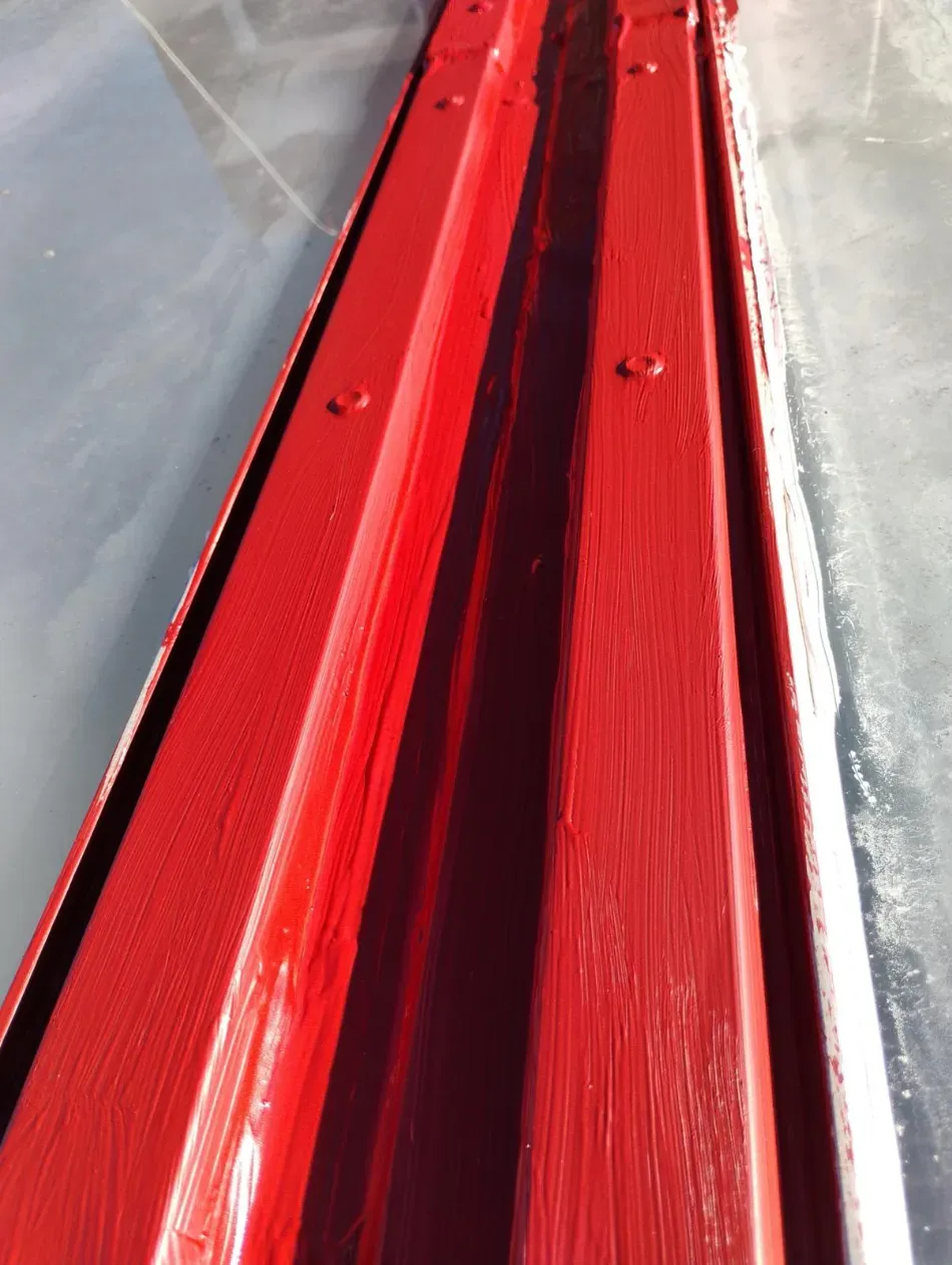Primer plano de una canaleta o canal de metal corrugado rojo entre superficies plateadas.
