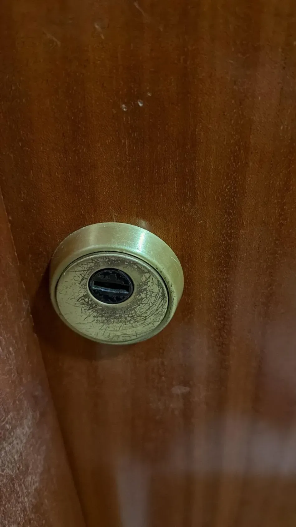 Primer plano de una mirilla de latón en una puerta de madera oscura.