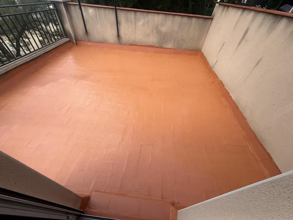 Terraza vacía en la azotea con suelo naranja y paredes de hormigón, vista desde una puerta.