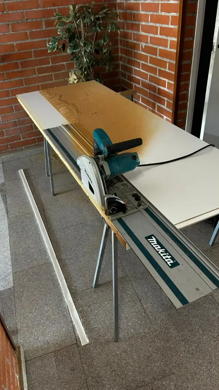Cortar una lámina de madera contrachapada con una sierra circular sobre un banco de trabajo en un garaje o patio.