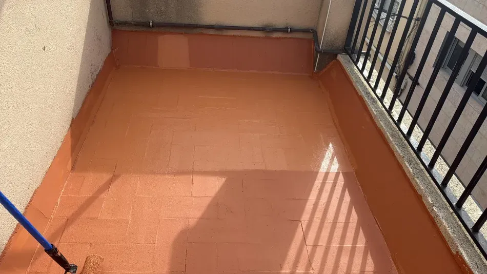 Balcón vacío con azulejos naranjas, barandilla negra y sombras proyectadas por la luz del sol.