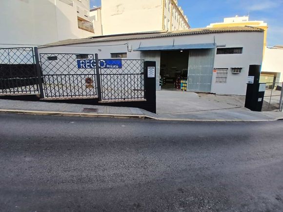 Edificio con portón y muelle de carga abierto; vista a la calle con cielo azul.
