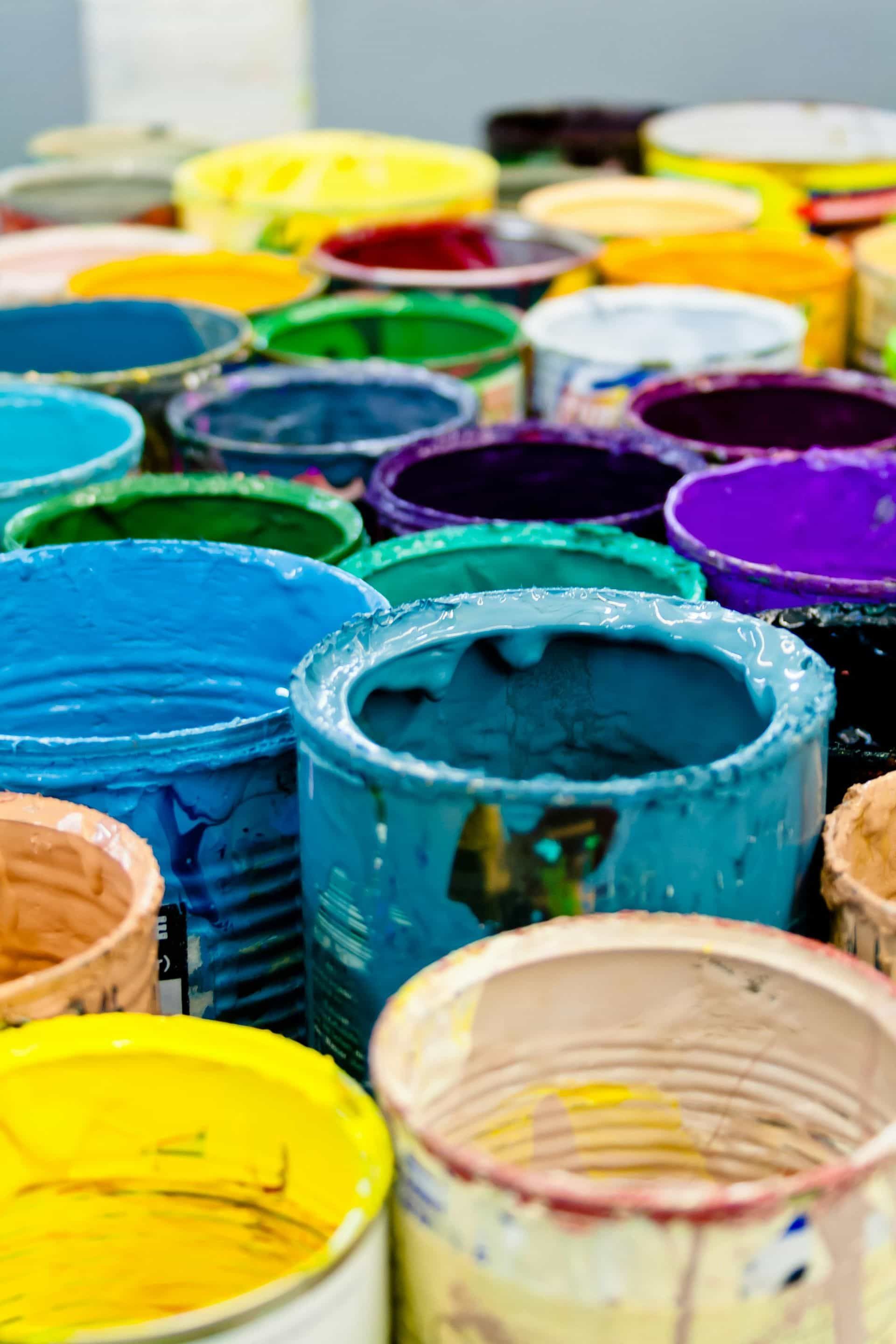 Abra latas de pintura de varios colores, incluidos azul, amarillo, verde y morado.