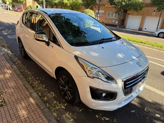 Peugeot 3008 blanco estacionado en una calle de la ciudad, llantas negras, espejo lateral plateado.