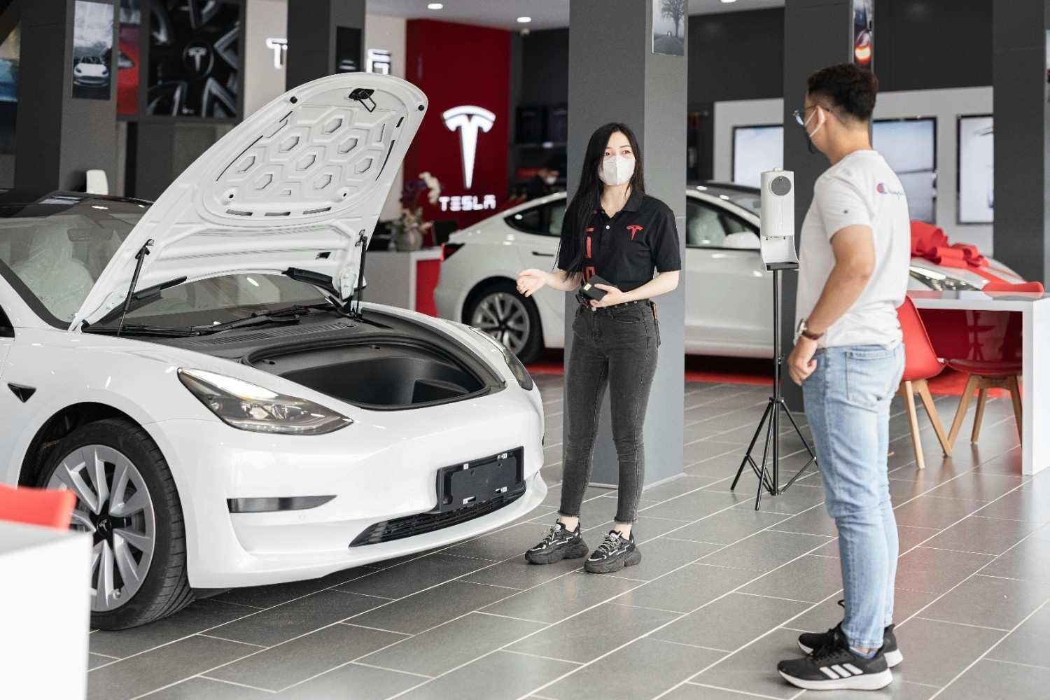 Una mujer en una sala de exposición de Tesla muestra las características de un coche