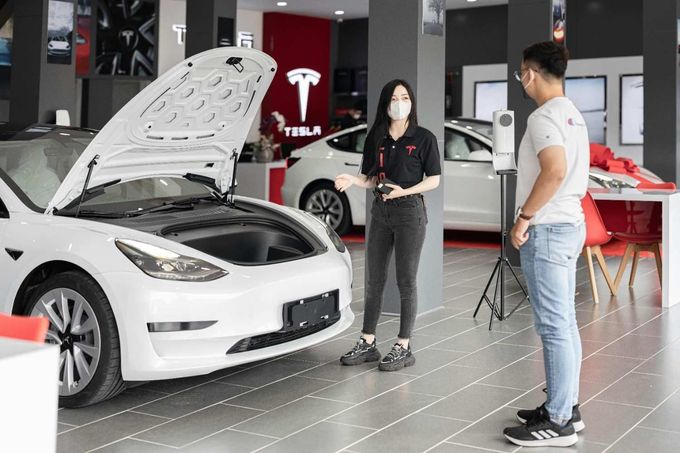 Una mujer en una sala de exposición de Tesla muestra las características de un coche