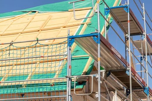 Échafaudages recouverts de bâches vertes sur un bâtiment en construction