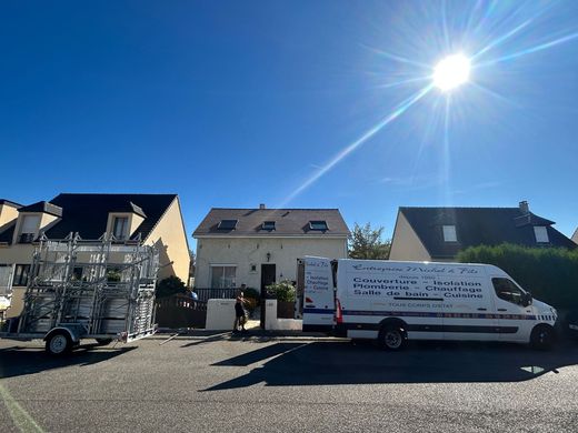 Une camionnette garée devant des maisons, sous un ciel radieux et ensoleillé, dans une rue résidentielle.