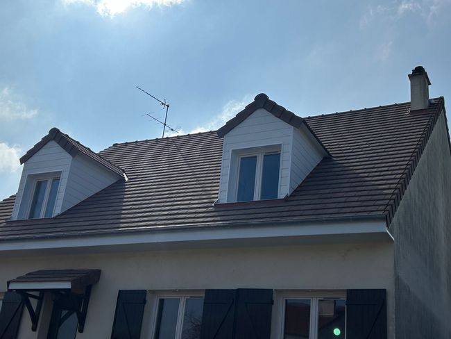 Toit de maison avec lucarnes sous un ciel d'un bleu éclatant.