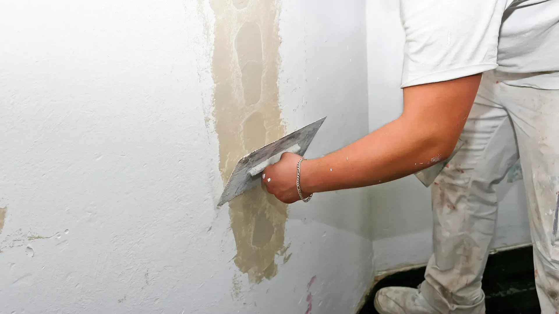 Persona que utiliza una paleta para aplicar yeso a una pared en un entorno interior.
