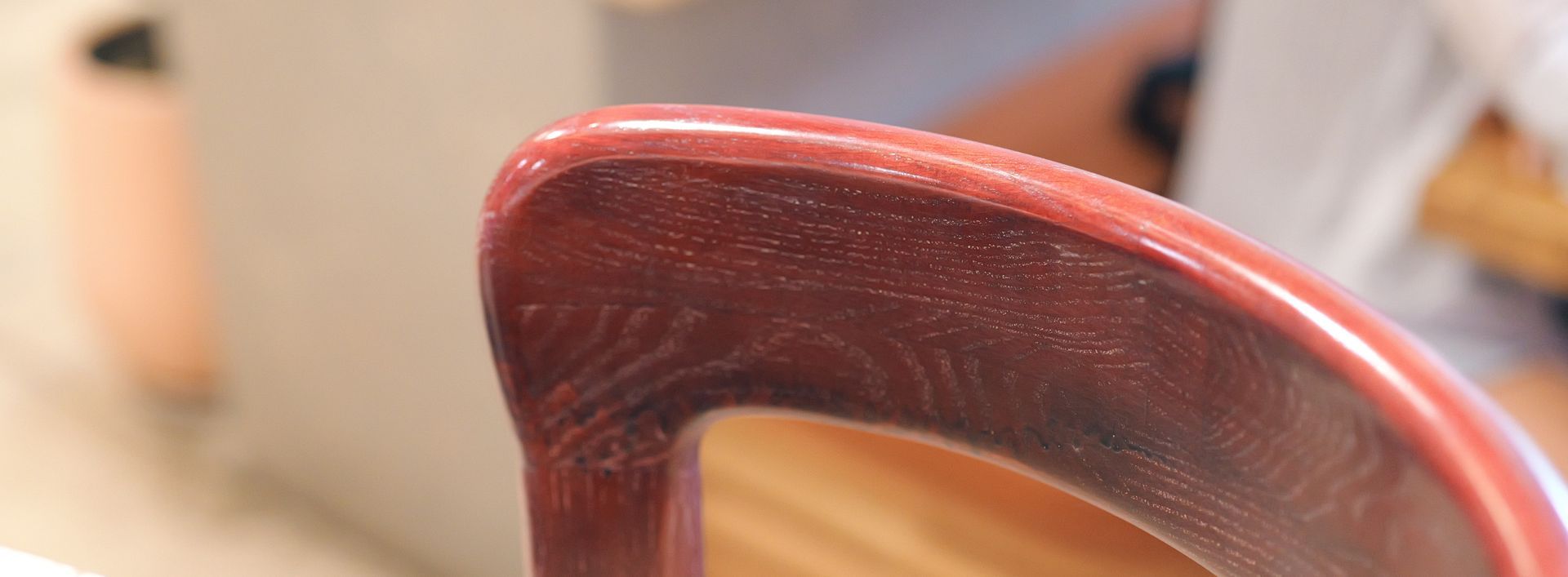 Gros plan sur un objet en bois poli, brun rougeâtre, à bord arrondi et à surface brillante