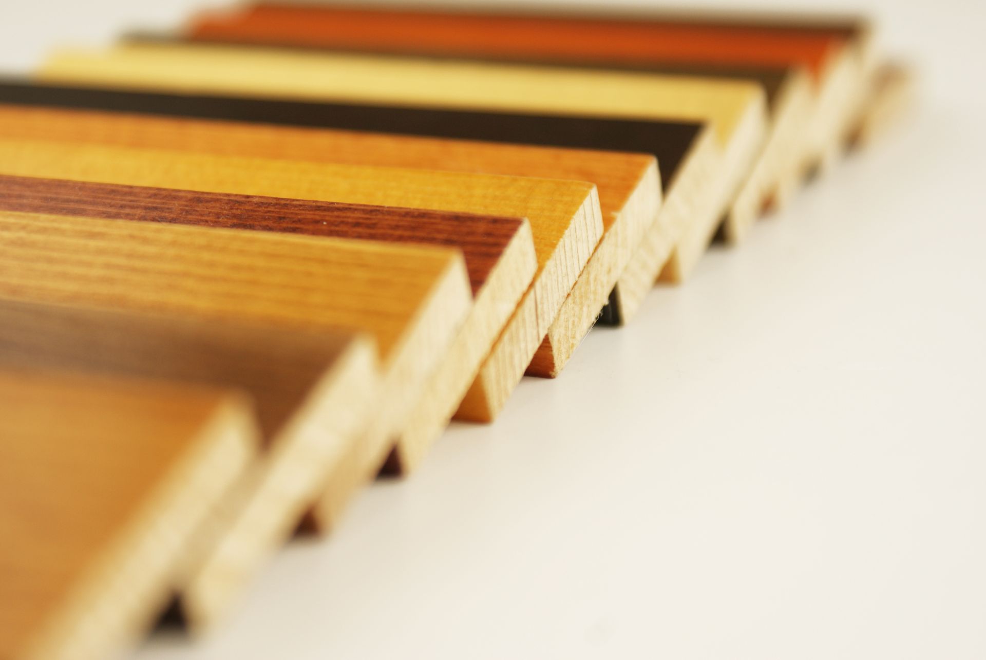 Des planches de bois de couleurs variées, disposées en rangée oblique, laissant apparaître différents grains et nuances de bois