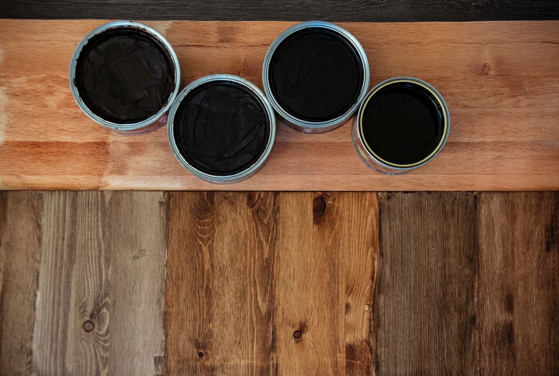 Quatre récipients ouverts contenant de la cire noire sur une surface en bois