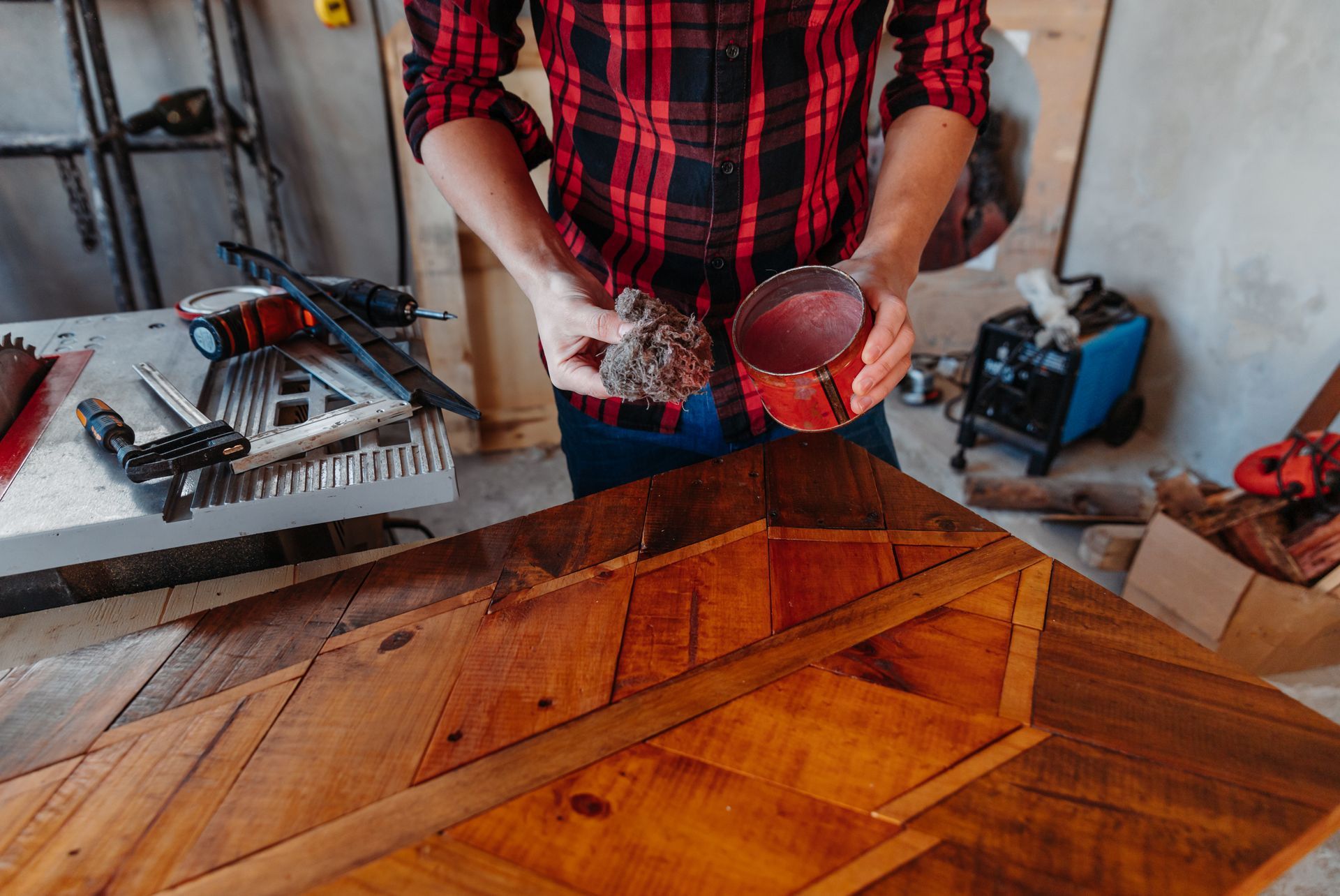 Une personne teintant une table en bois avec un chiffon dans un atelier