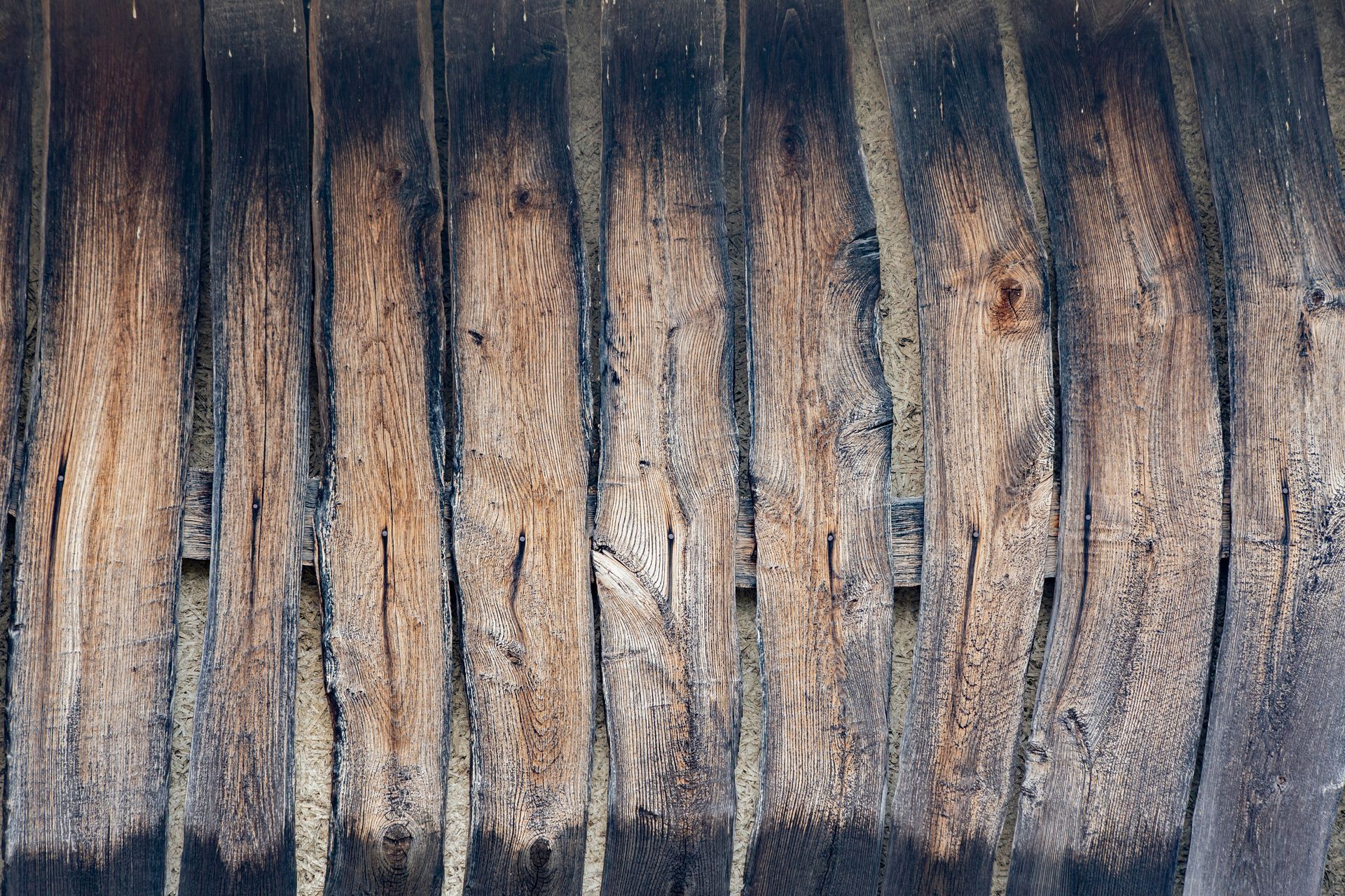 Planches de bois patinées, disposées verticalement, marquées par un départ de feu