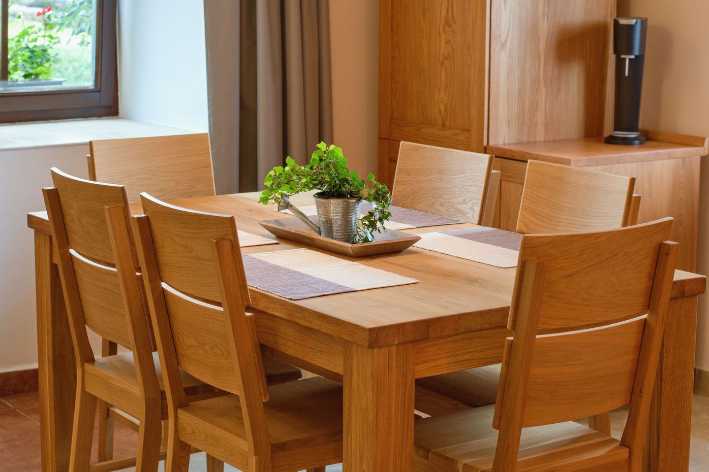 Table à manger en bois pour six personnes avec un centre de table, près d'une fenêtre