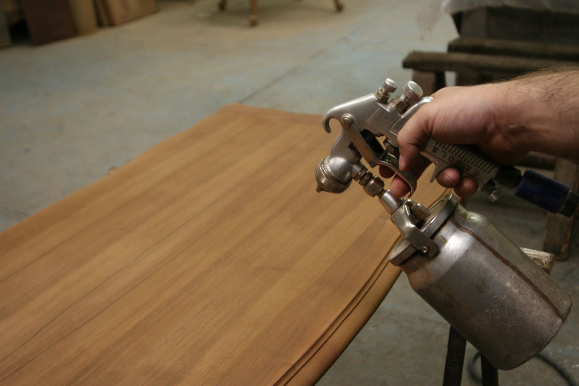 Un pistolet applique de la teinture sur une planche de bois.
