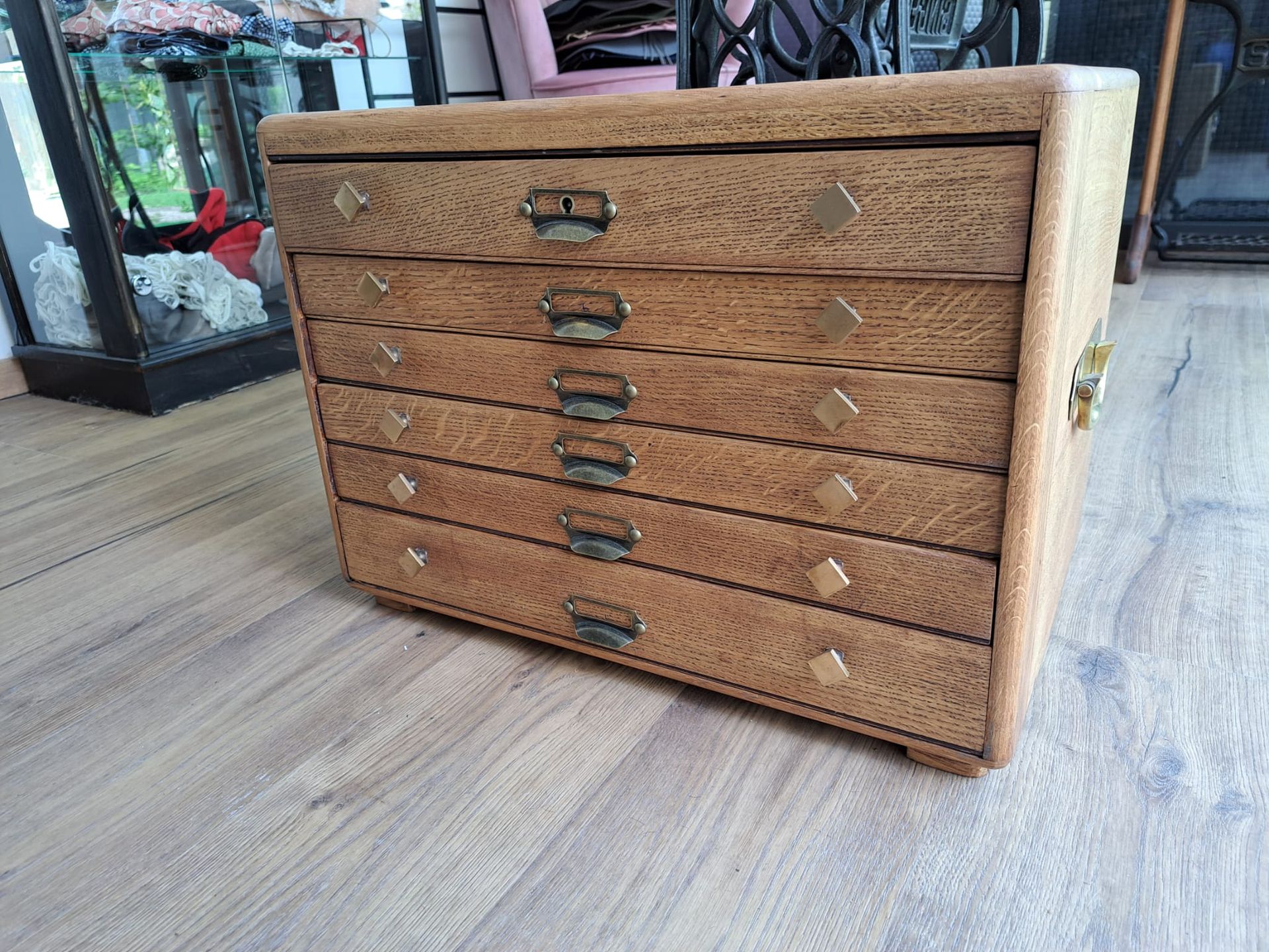 Commode en bois à six tiroirs coulissants, quincaillerie en laiton et ornements en forme de losange, posée sur un plancher en bois