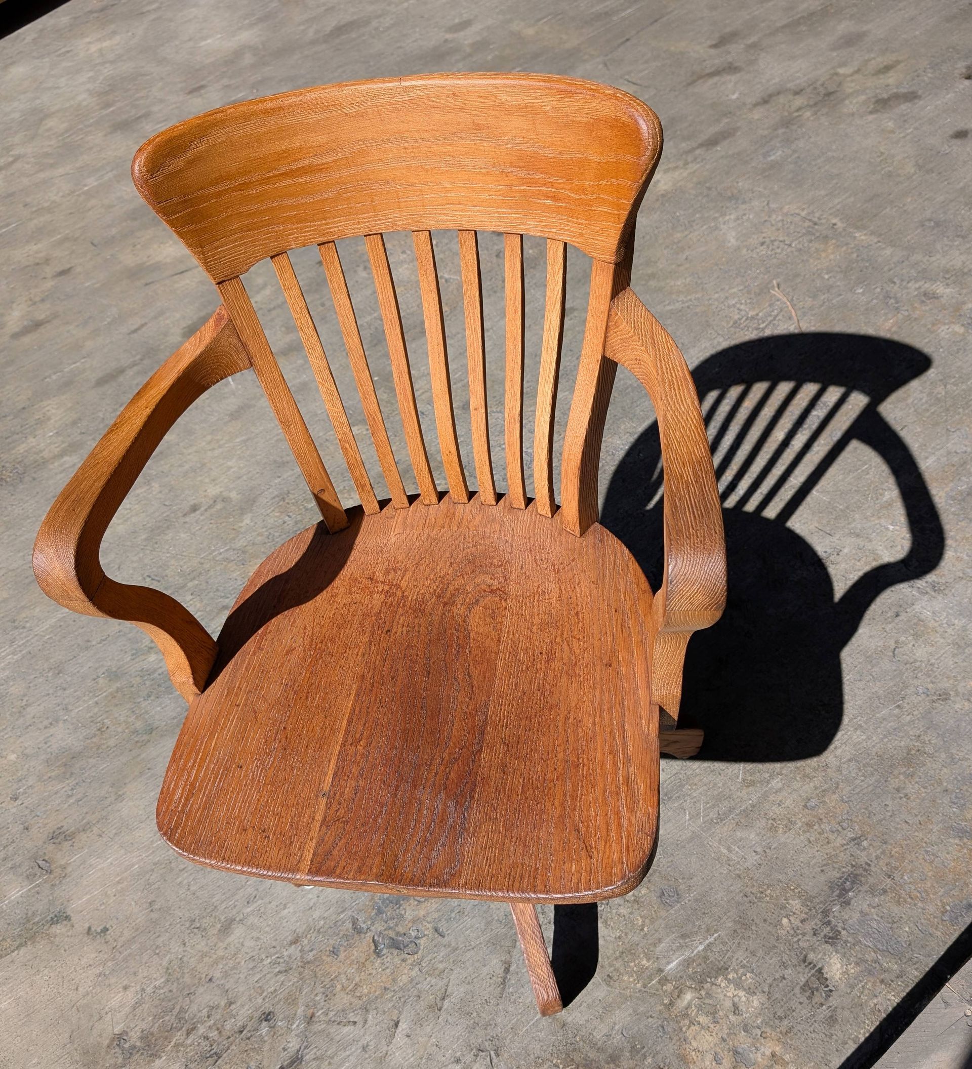 Vue de dessus d'une chaise en bois brun clair, avec un dossier et des accoudoirs incurvés