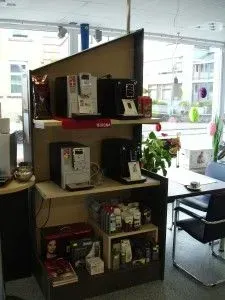 Regale zur Präsentation verschiedener Gegenstände in einem hellen Büro oder Café-Sitzbereich