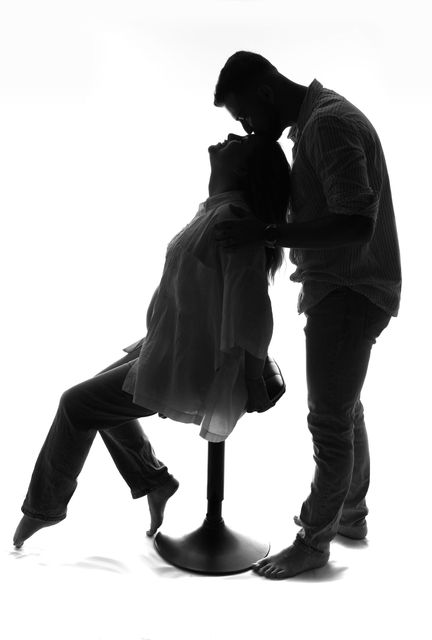 Couple enlacé en silhouette, blotti l’un contre l’autre sur un fond blanc.