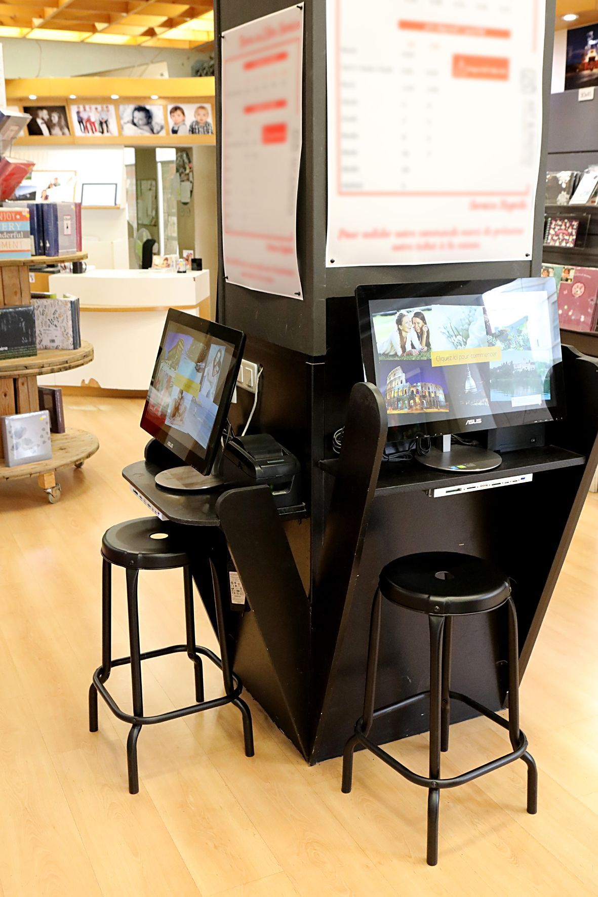 Borne en libre-service avec deux écrans et des tabourets dans un magasin, affichant des menus lumineux sur un comptoir noir.