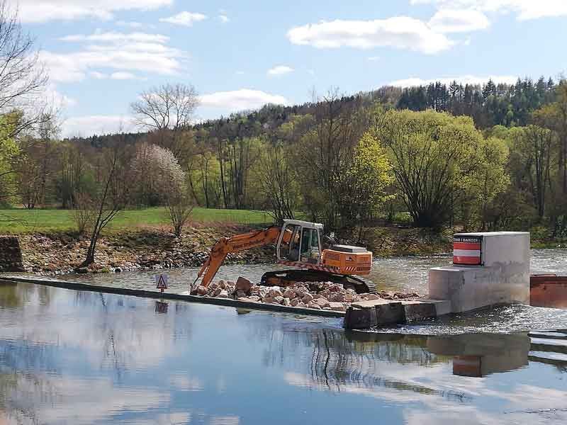 Bagger entfernt Steine aus Flußbett