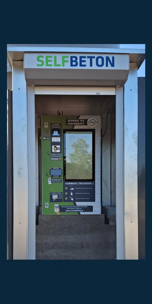 Une machine de distribution de béton automatisée Selfbeton, installée dans un kiosque métallique.