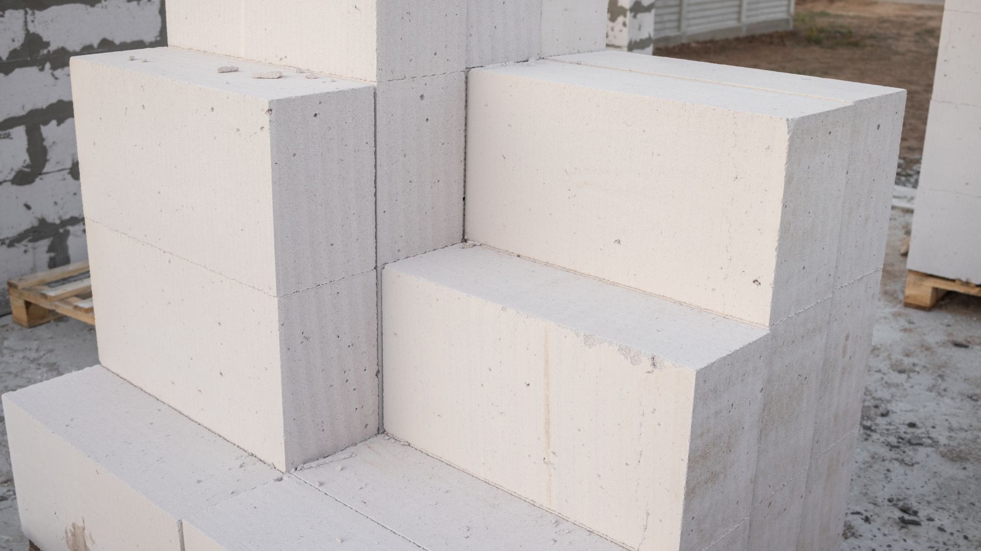 Des piles de blocs de béton gris disposées sur des palettes en bois.