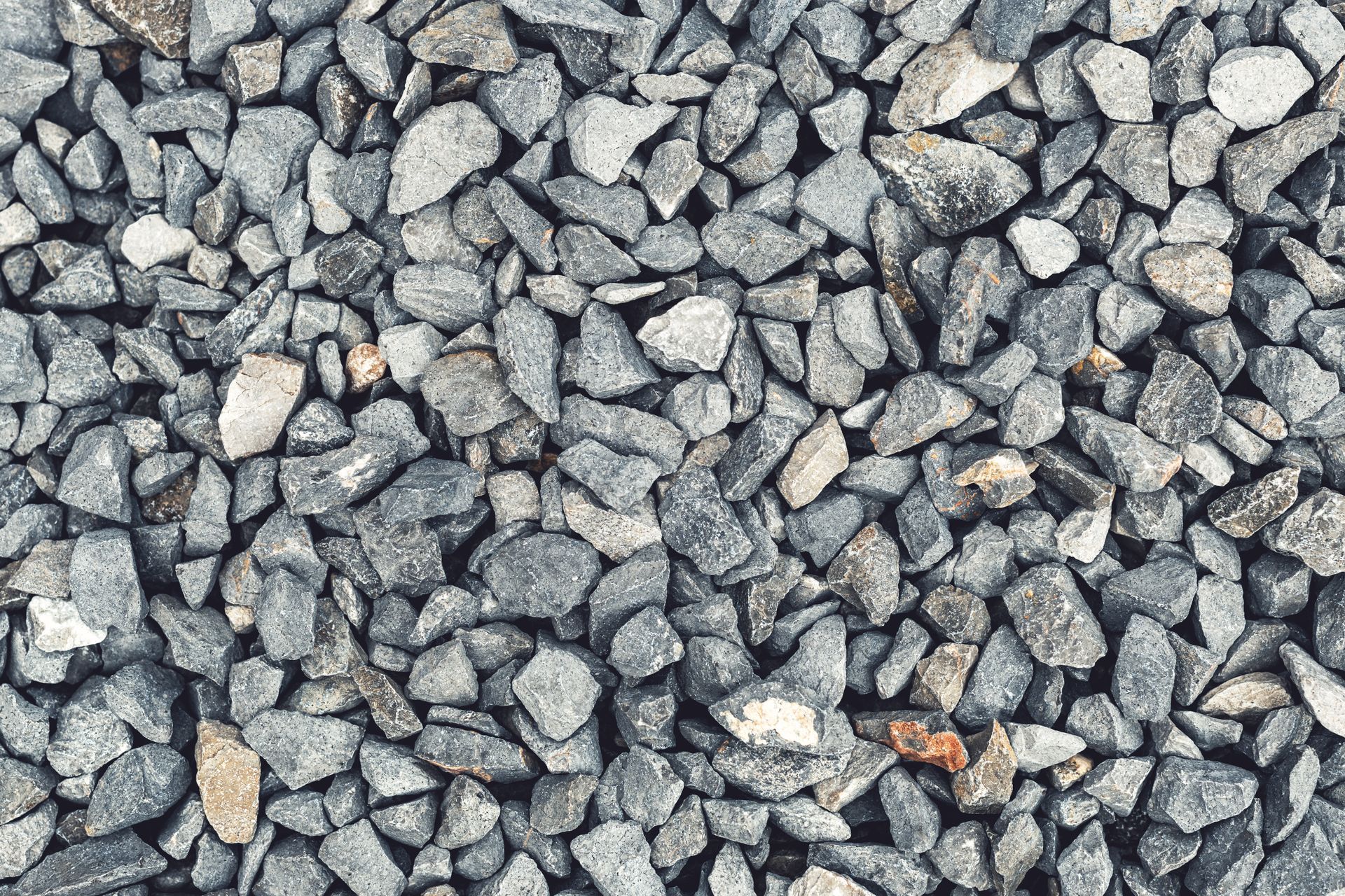 Gros plan sur un tas de petits cailloux ou de gravier gris anguleux.