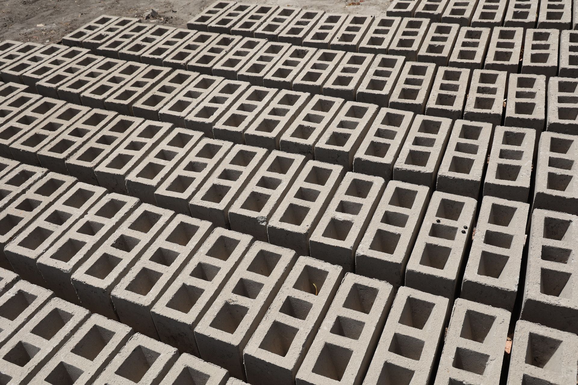 Vue en plongée de nombreux blocs de béton gris et rectangulaires, disposés en rangées nettes et répétitives.