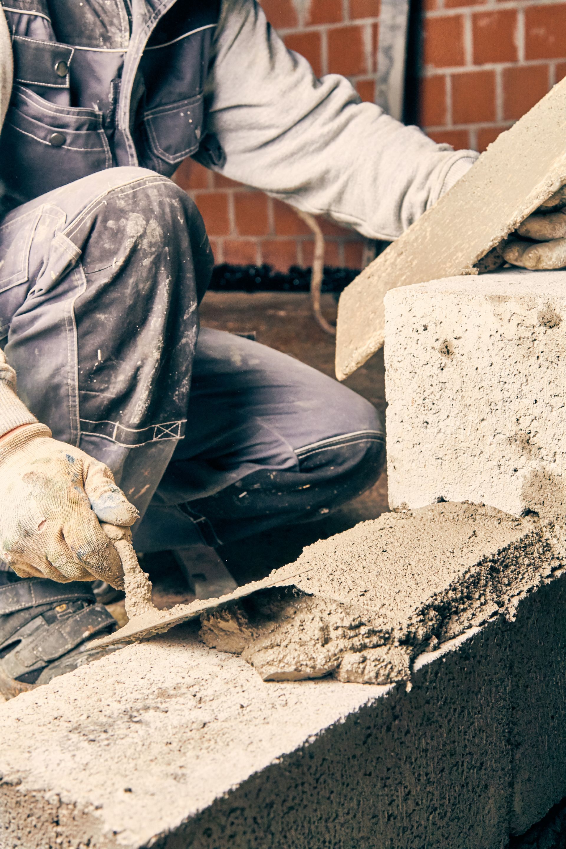 Un maçon étale du mortier sur un parpaing