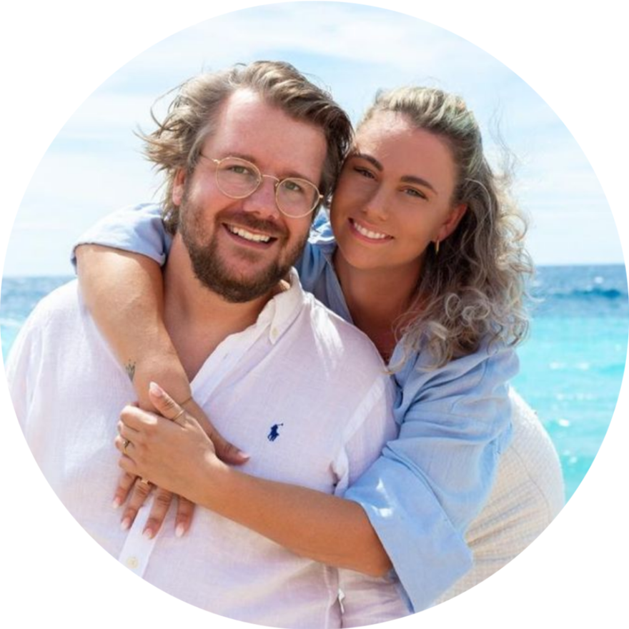 Smiling couple embracing on a sunny beach with turquoise water in the background