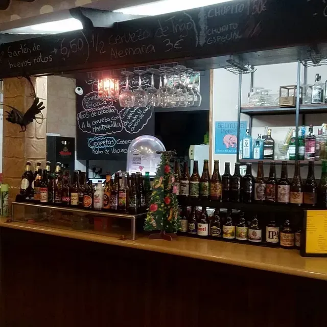Bar con varias botellas de cerveza, vasos colgados encima y un pequeño árbol de Navidad.
