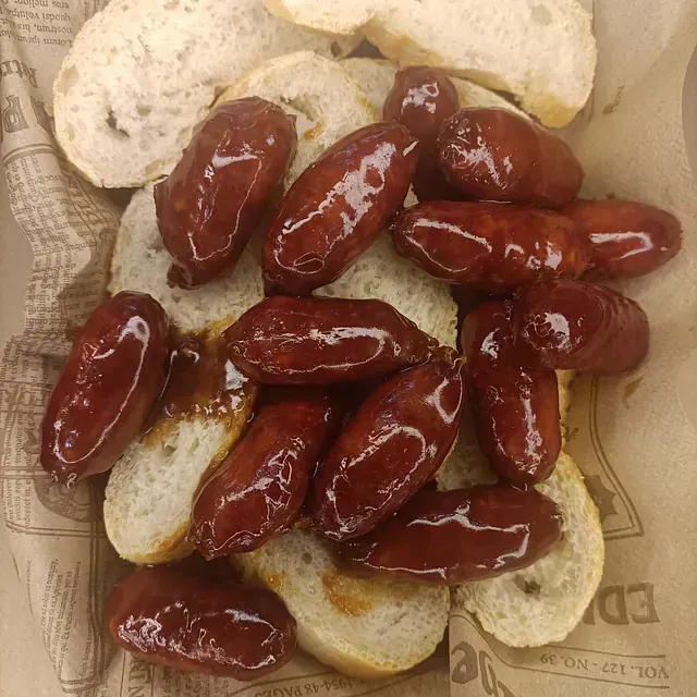Mini salchichas sobre pan de molde en una cesta forrada con papel.