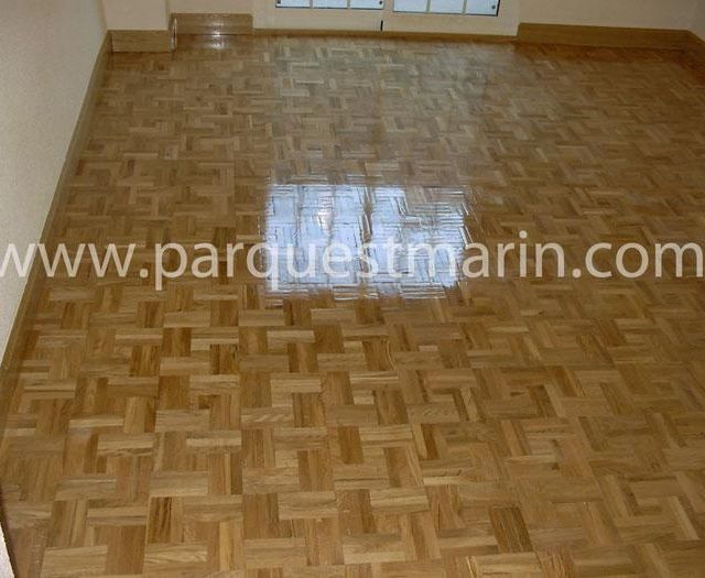 Una habitación vacía con suelo de madera y el sitio web www.parquetmarin.com