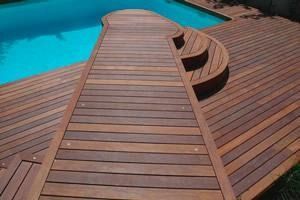 Una terraza de madera con escaleras que conducen a una piscina.
