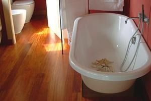 Hay una bañera en el baño con suelo de madera.