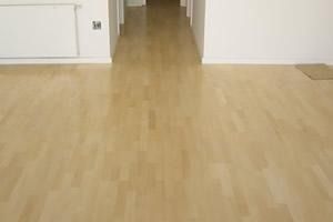 Un pasillo vacío con suelo de madera y paredes blancas.