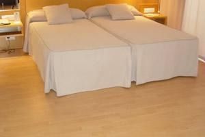 Una habitación de hotel con dos camas y suelo de madera.